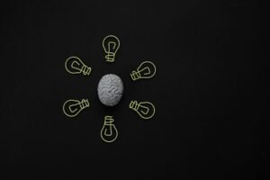 Conceptual photo of a brain surrounded by light bulb clips on black background.