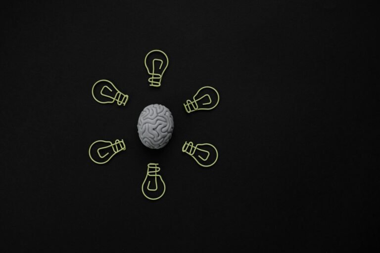 Conceptual photo of a brain surrounded by light bulb clips on black background.